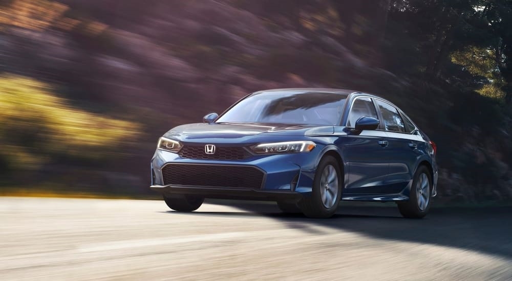 Blue 2026 Honda Civic driving down an open road.