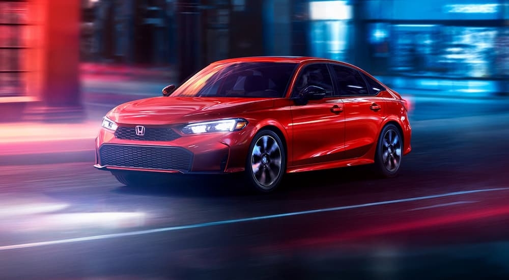 Red 2026 Honda Civic driving down an open road.