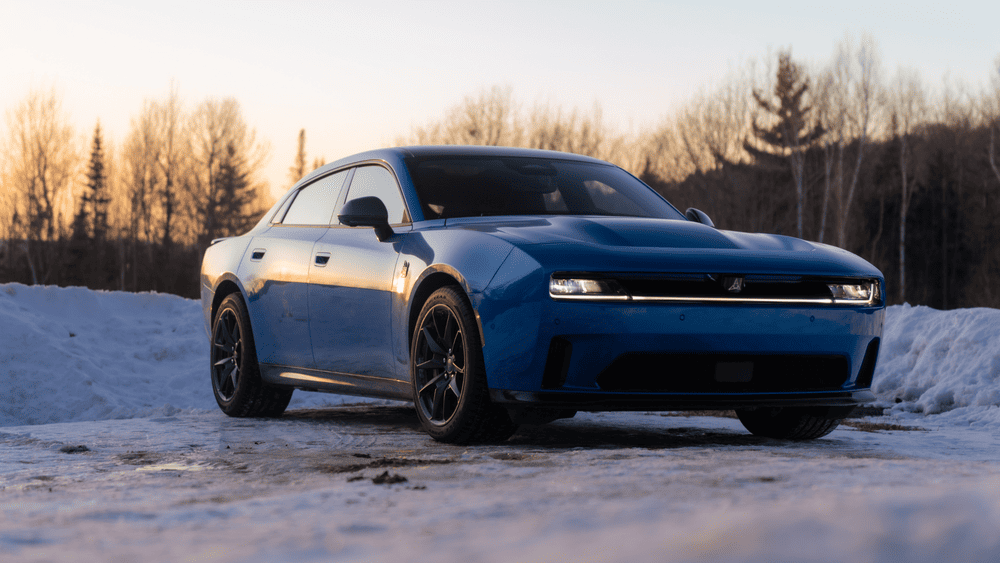 2026 Dodge Charger Daytona in blue with full-width LED lightbar, blacked-out grille, and dark alloy wheels parked on snow at sunset, highlighting big design changes Margate FL drivers may notice