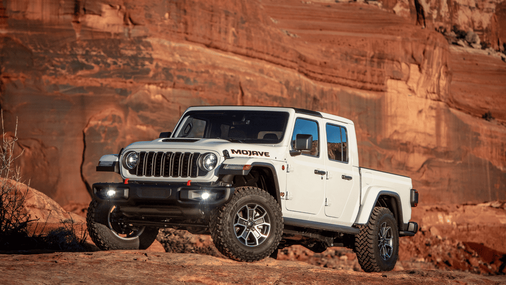 2026 Jeep Gladiator Mojave in white parked on red rock terrain with off-road tires and crew cab pickup bed, built for serious towing strength near Margate FL compared to the Ford Ranger