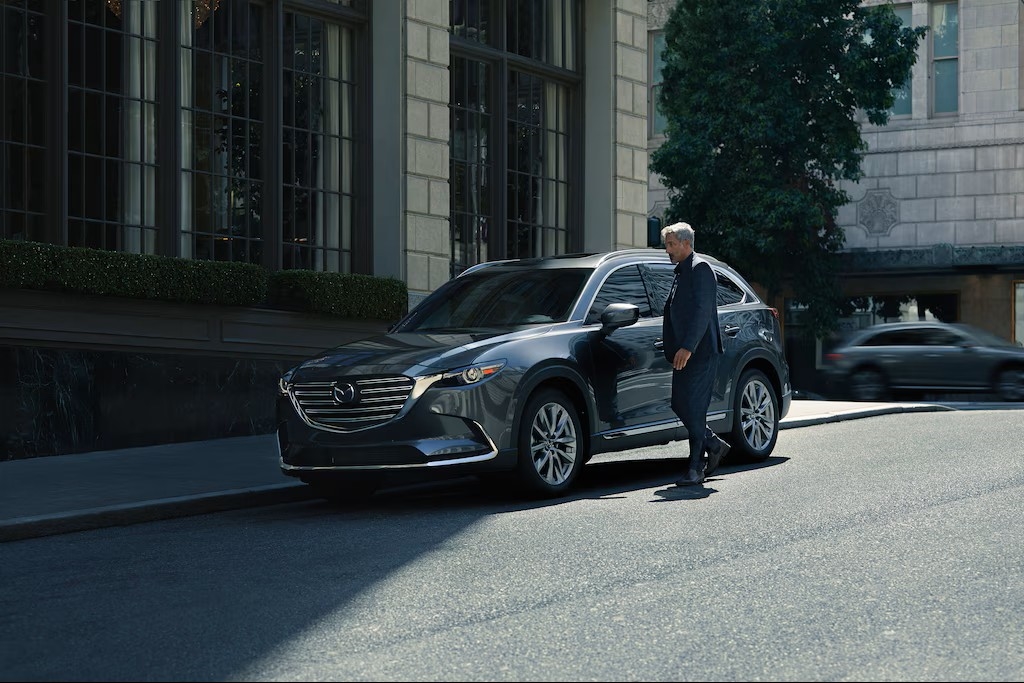 Person standing next to a Mazda