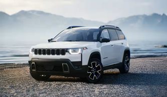 Jeep Cherokee parked by a lake and mountain