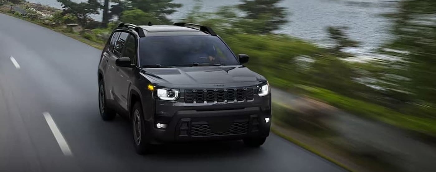 A black 2026 Jeep Cherokee driving on a highway.