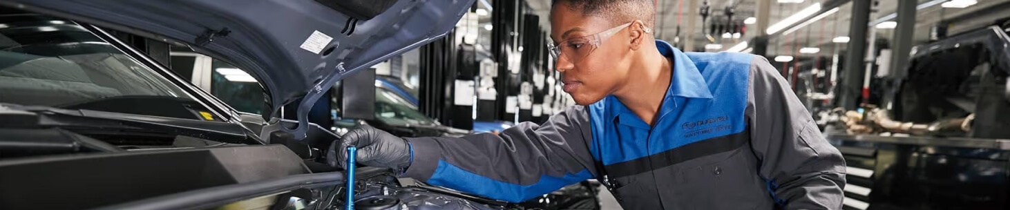 A Subaru Certified Technician inspects under the hood of a Subaru vehicle.