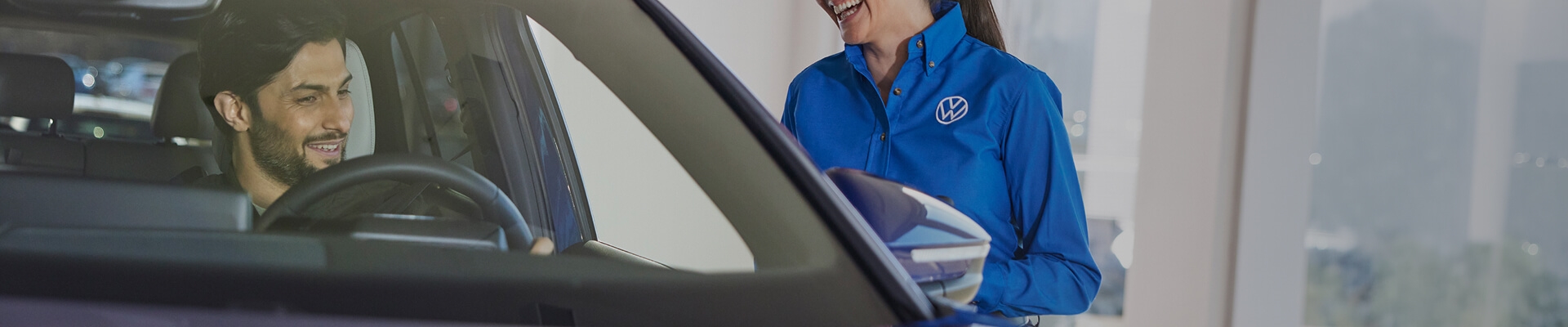 A sales interaction with a client inside a Volkswagen vehicle in a dealership showroom.