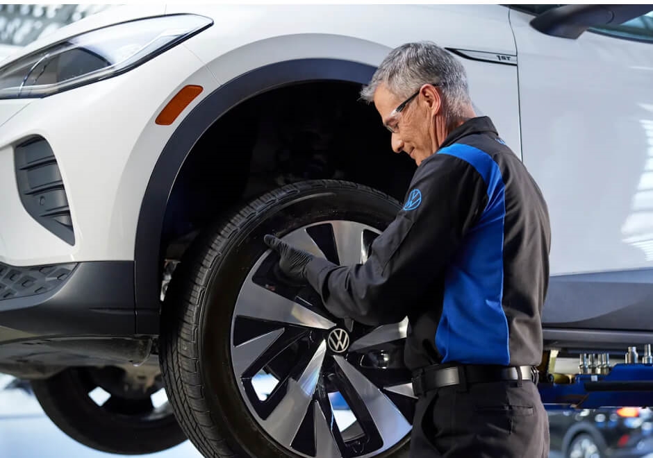 A VW Technician inspects a VW vehicle's tires.