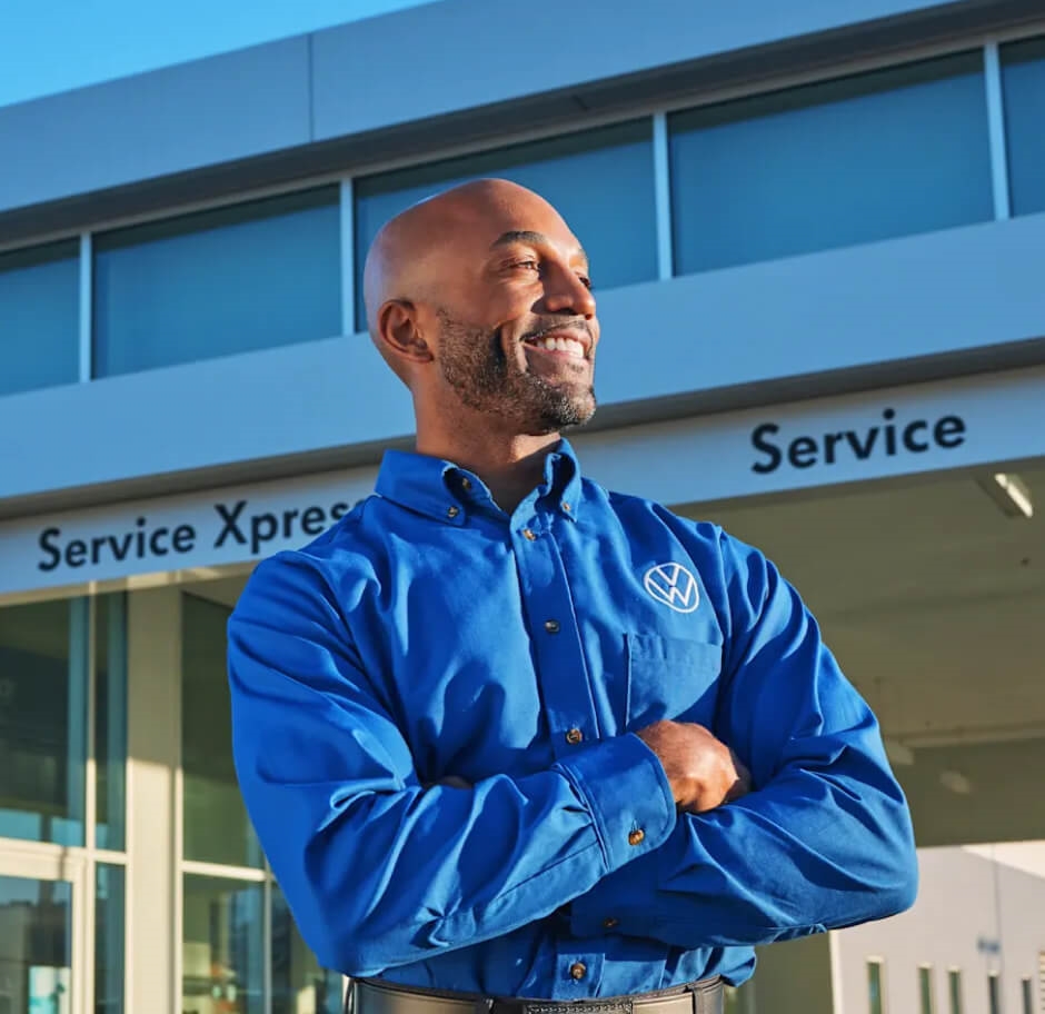 A man in a blue VW shirt smiles outside a VW Certified service center.