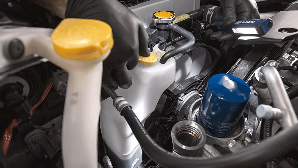 Gloved technician inspecting the brake-fluid reservoir with a Subaru inspection light during a service check.