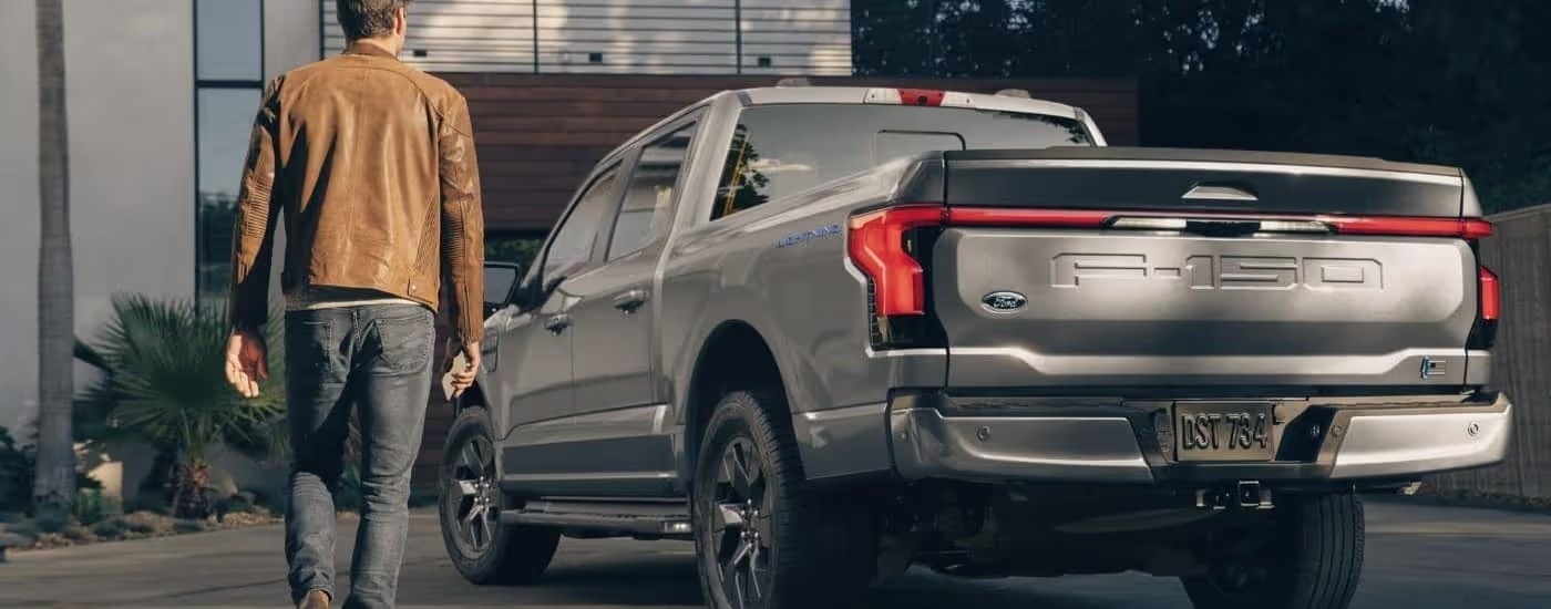 A grey 2022 Ford F-150 Lightning is shown from the rear on a driveway.