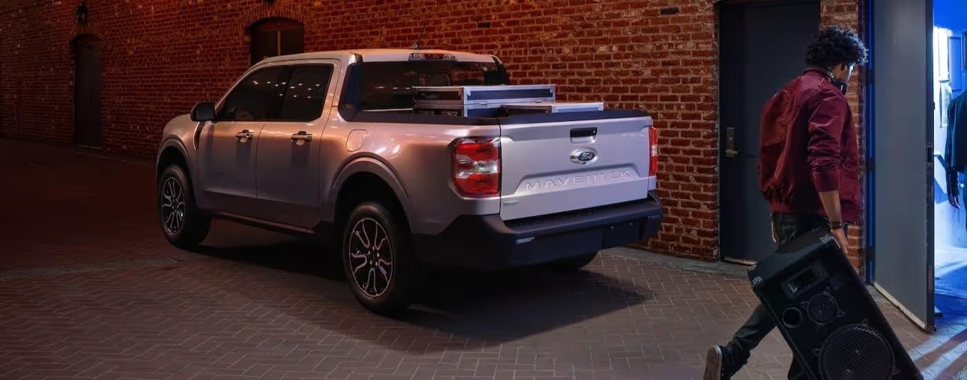 A silver 2025 Ford Maverick is shown parked near a brick building.