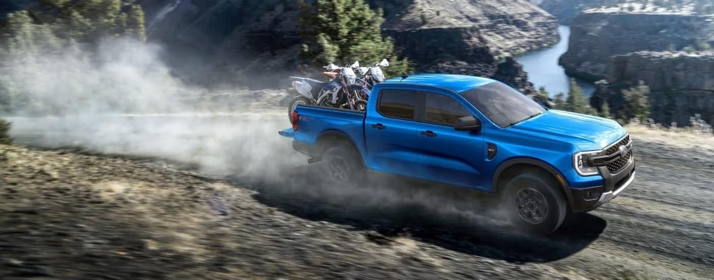 A blue 2025 Ford Ranger XLT is shown kicking up dust on a trail