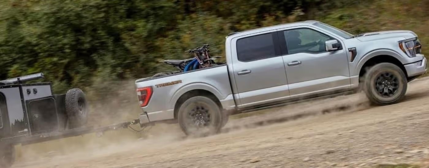 A silver 2023 Ford-F-150 Tremor is shown towing a trailer.