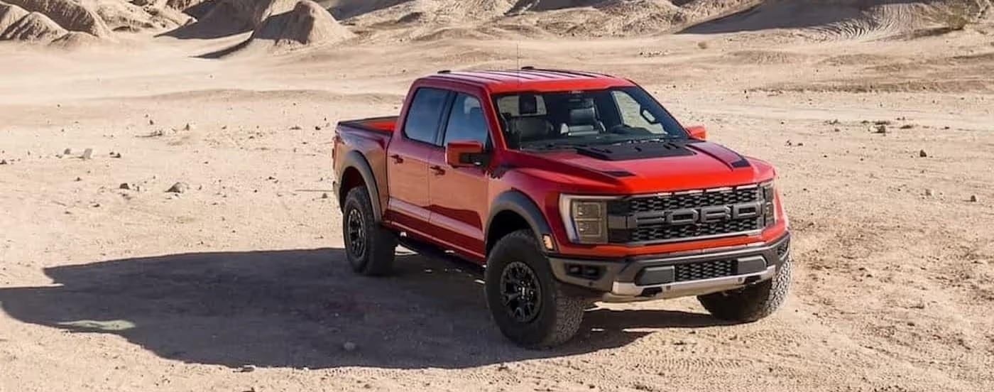 A red 2023 Ford F-150 Raptor is shown parked off-road.