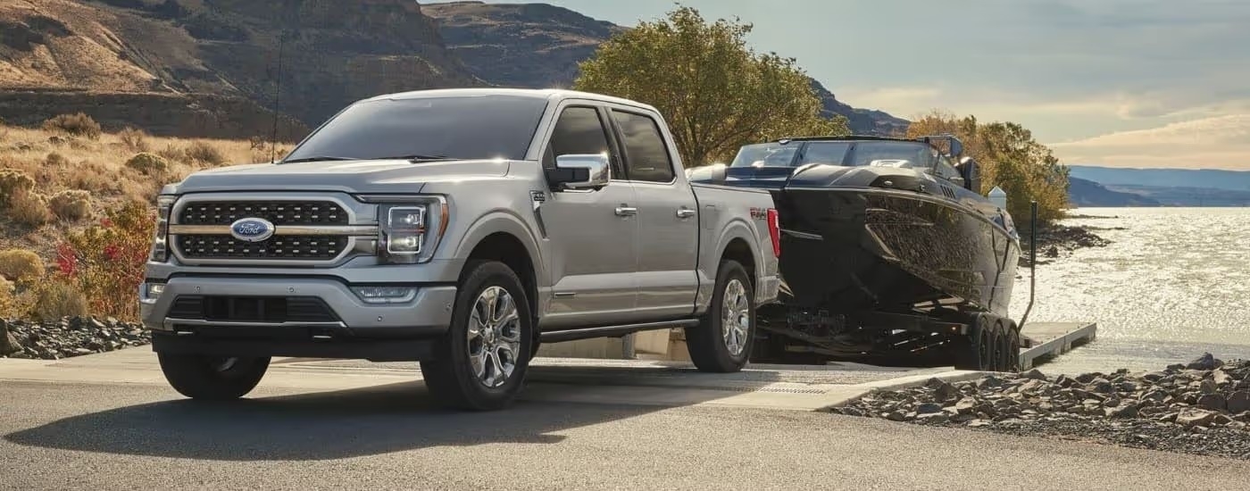 A silver 2023 Ford F-150 is shown towing a boat after visiting a Ford F-150 dealer near Dunwoody, GA.