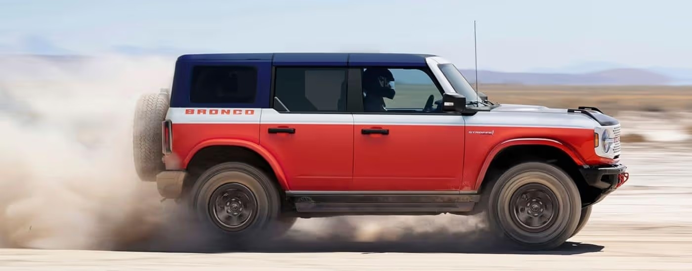 Red 2026 Ford Bronco Stroppe edition driving through a salt pan in the desert