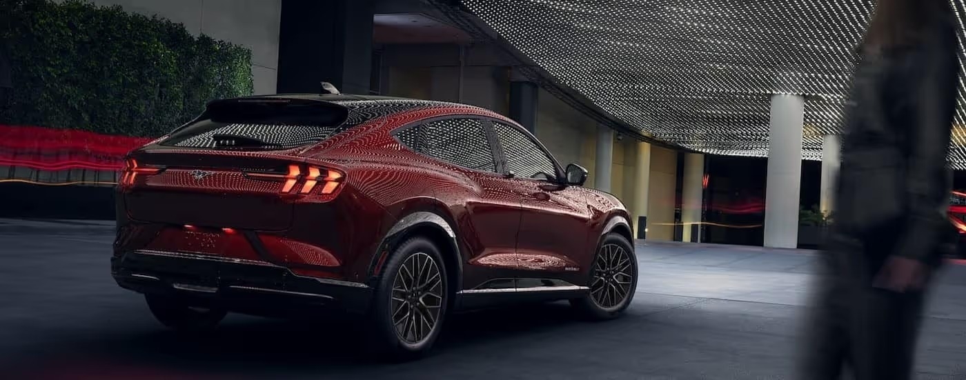 A red 2024 Ford Mustang Mach-E is shown parked under a well lit ceiling.