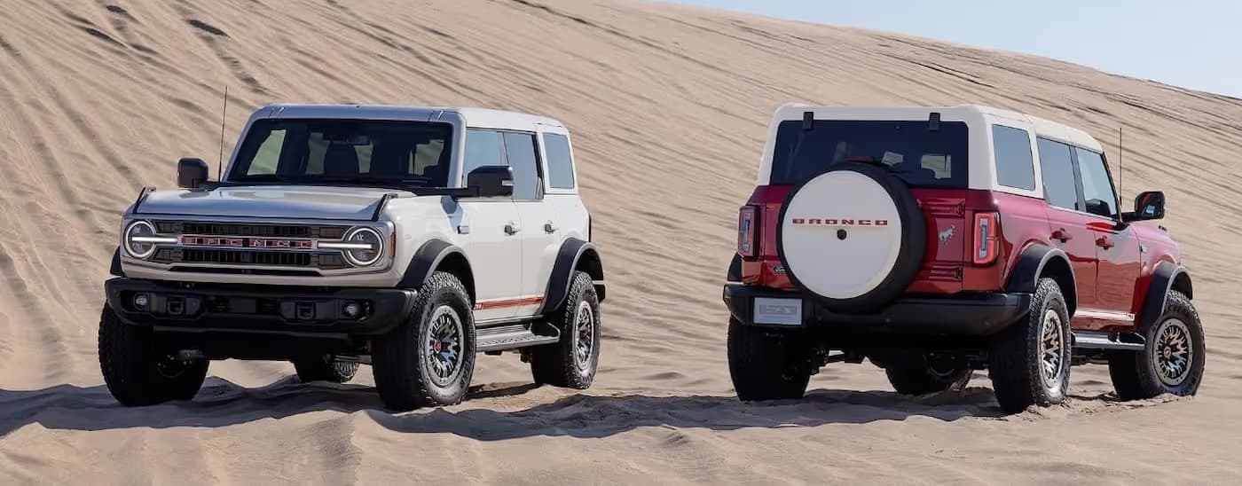A red and a white 2026 Ford Bronco facing opposite directions offroad.