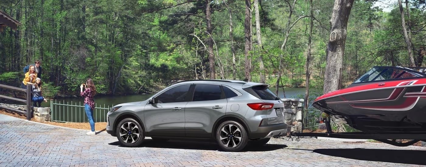 A silver 2025 Ford Escape Platinum towing a boat.