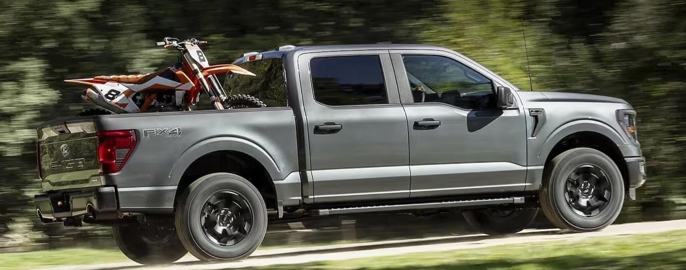 A gray 2024 Ford F-150 is shown driving off-road.