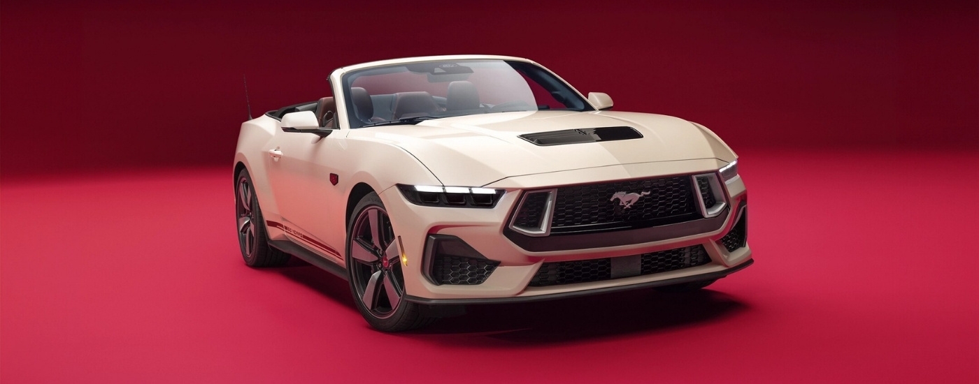 White 2025 Ford Mustang 60th Anniversary parked against a pink background