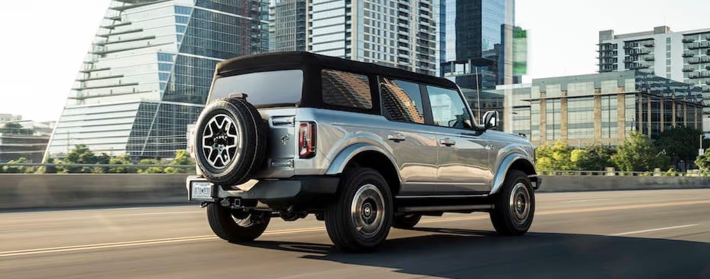 A silver 2024 Ford Bronco for sale is shown from the rear at an angle.