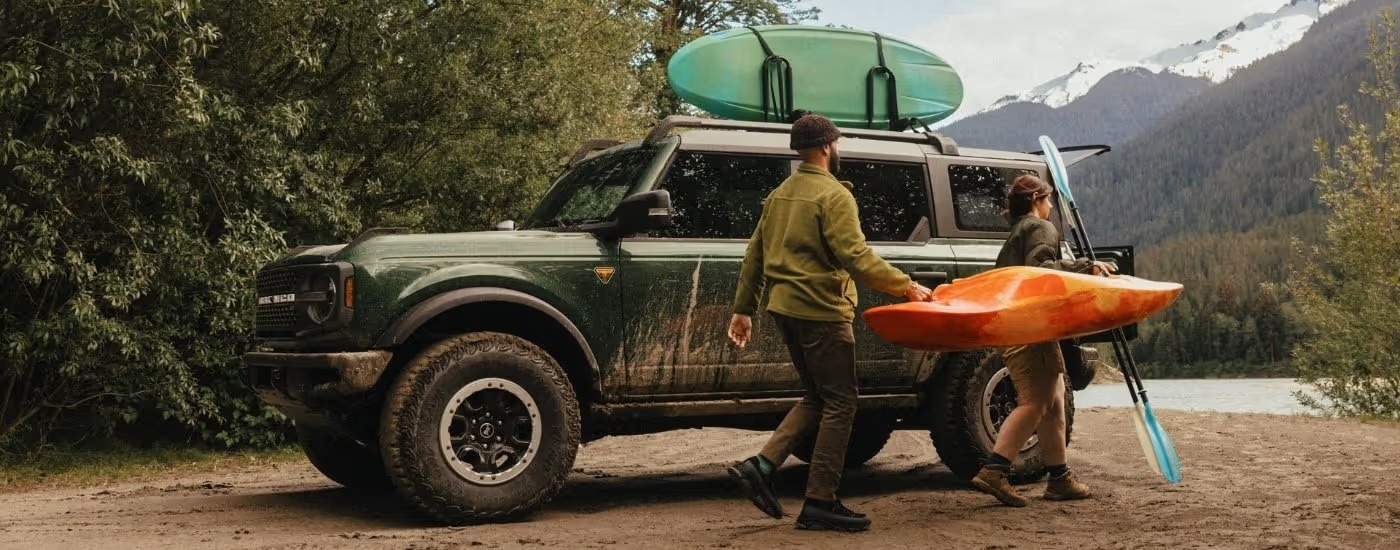 A green 2025 Ford Bronco Badlands parked near a lake.