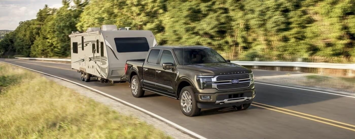 A black 2024 Ford F-150 Platinum Plus towing a trailer.