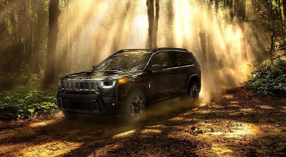 Black 2026 Jeep Cherokee parked off-road in a forest.