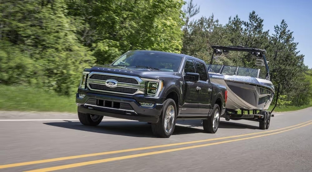 A grey 2023 Ford F-150 Limited is shown from the front while towing a boat after leaving a Ford F-150 dealer near East Cobb, GA.