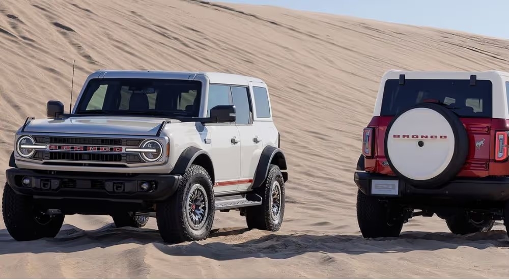A front-facing white 2026 Ford Bronco and a rear-facing red 2026 Ford Bronco.