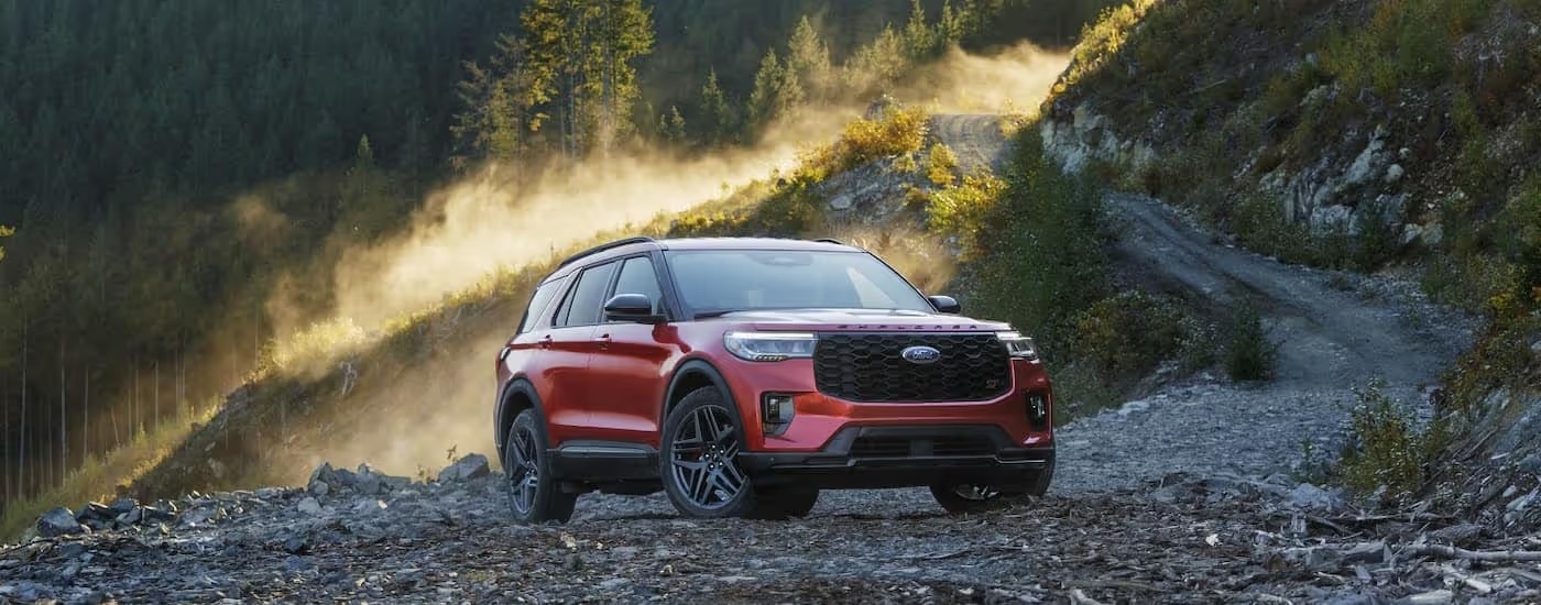 A red 2025 Ford Explorer parked in a rocky clearing.