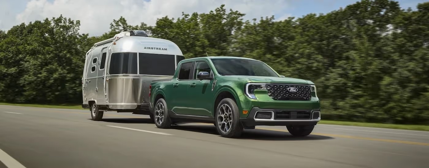 A green 2025 Ford Maverick is shown towing an Airstream trailer.