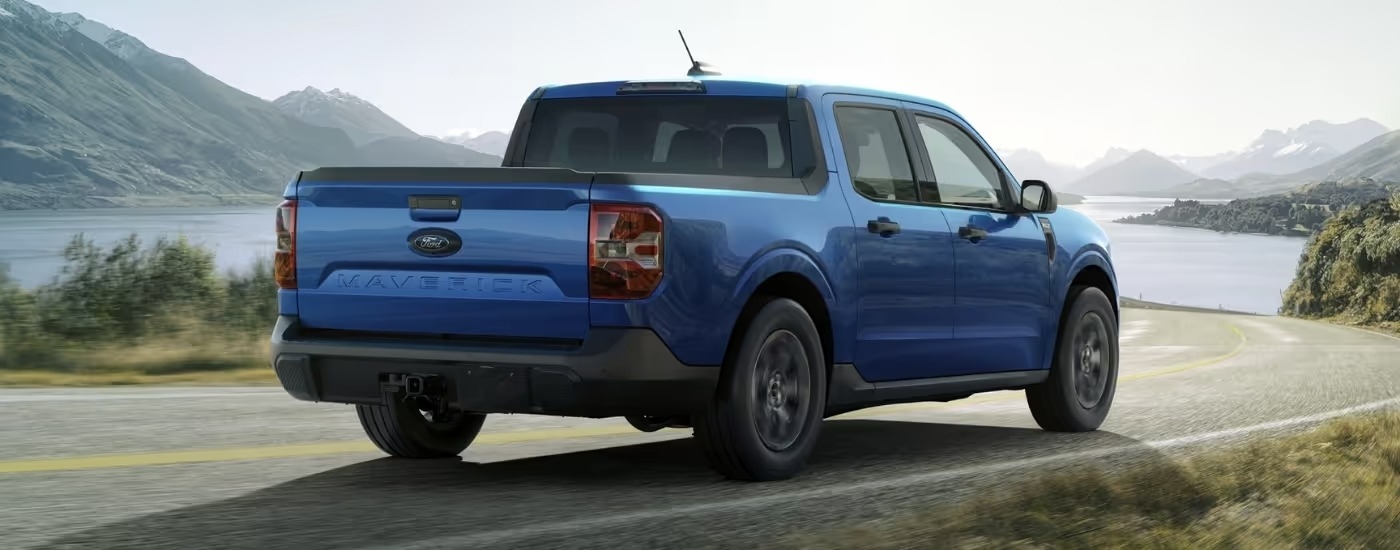 A blue 2025 Ford Maverick for sale is shown driving on a highway.
