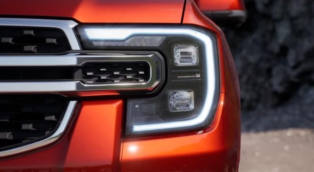 A close up shows the driver side headlight on an orange 2024 Ford Ranger Raptor after visiting a Dunwoody Ford dealer.