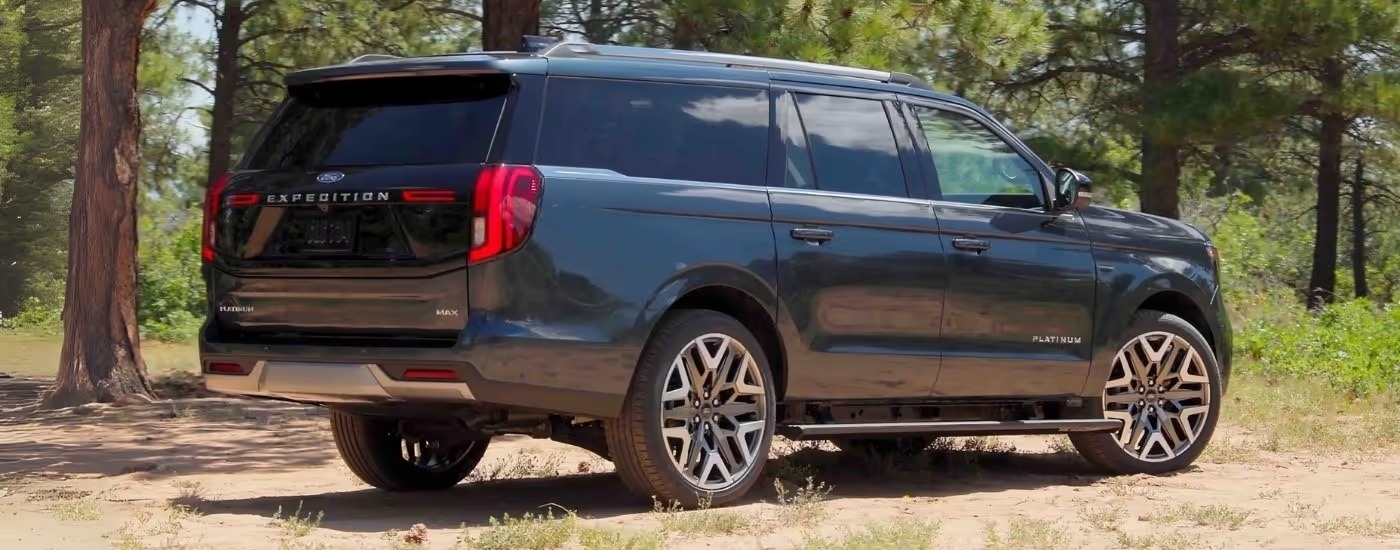 A dark blue 2025 Ford Expedition MAX Platinum is shown parked near trees.