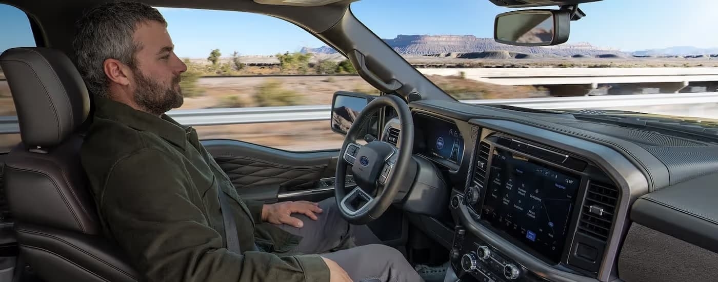 A person driving in a 2025 Ford F-150 STX