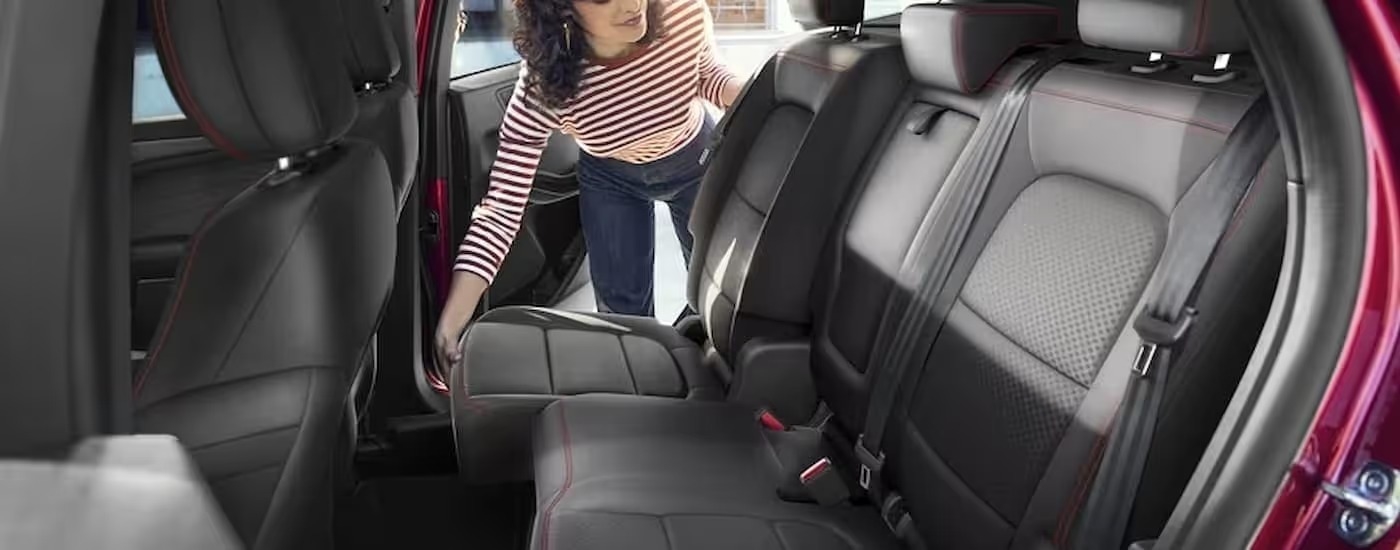 A woman is shown adjusting the rear row of seating in a red 2024 Ford Escape.