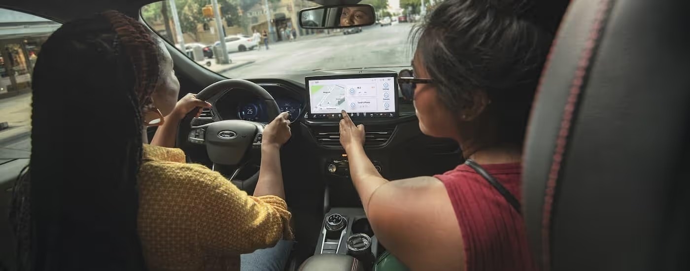 Two friends are shown driving in a 2024 Ford Escape on a city street.