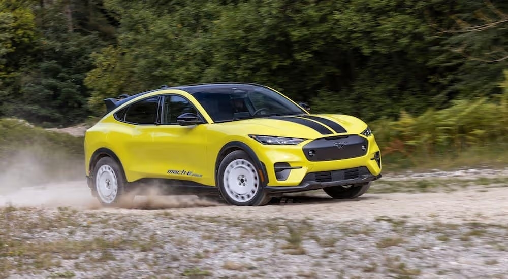 A yellow 2024 Ford Mustang Mach-E Rally is shown from the side while off-road.