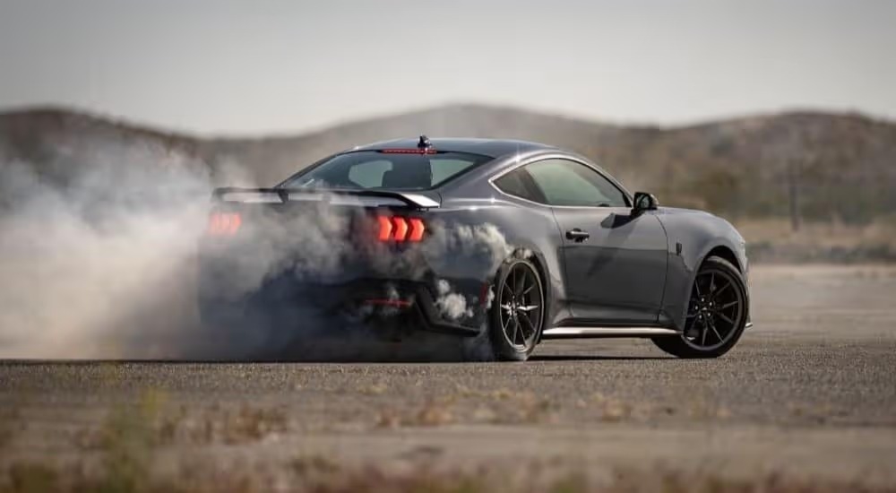 A black 2024 Ford Mustang Dark Horse is shown performing a burnout.