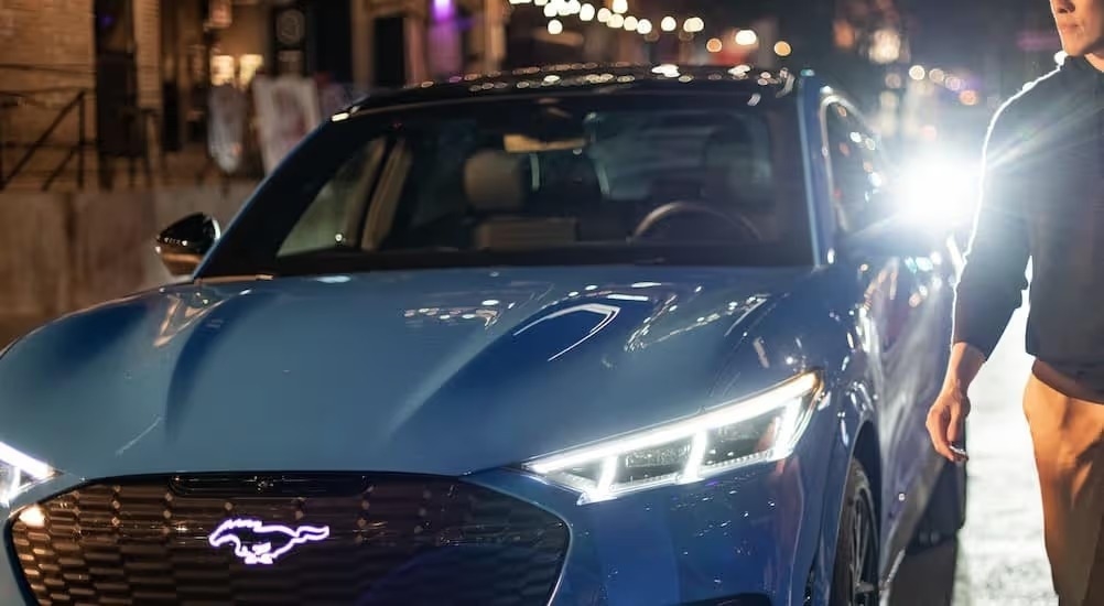 A person is shown walking near a blue 2024 Ford Mustang Mach-E GT.