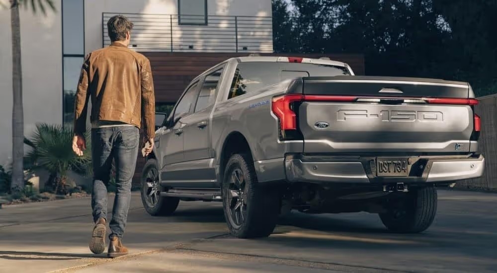 A person is shown from a rear angle walking towards a grey 2024 Ford F-150 Lighting parked.