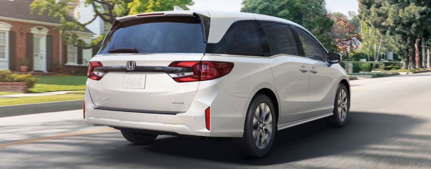 A white 2026 Honda Odyssey Elite shown from rear driving in suburbs.