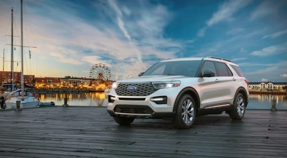 A silver 2024 Ford Explorer parked on a pier near an amusement park.