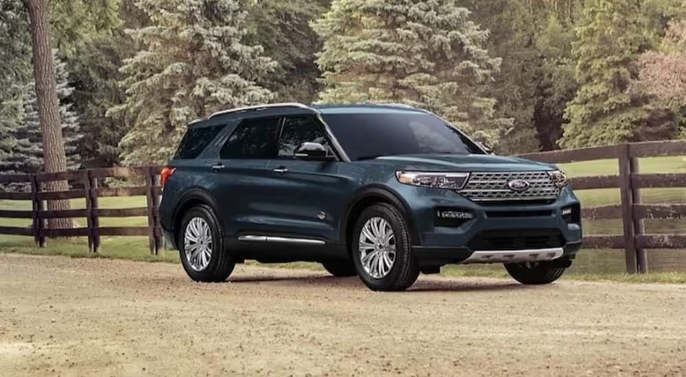 A green 2024 Ford Explorer shown parked next to a fence in a field.