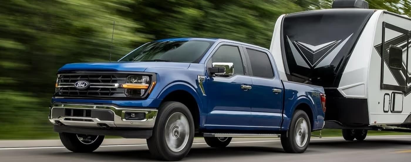 A blue 2024 Ford F-150 towing a trailer