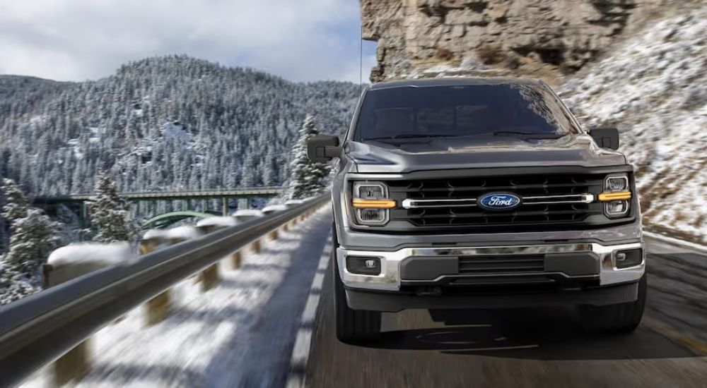 Dark grey 2025 Ford F-150 STX driving up a mountain road.