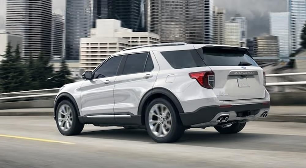 A white 2024 Ford Explorer Platinum is shown driving on a highway.