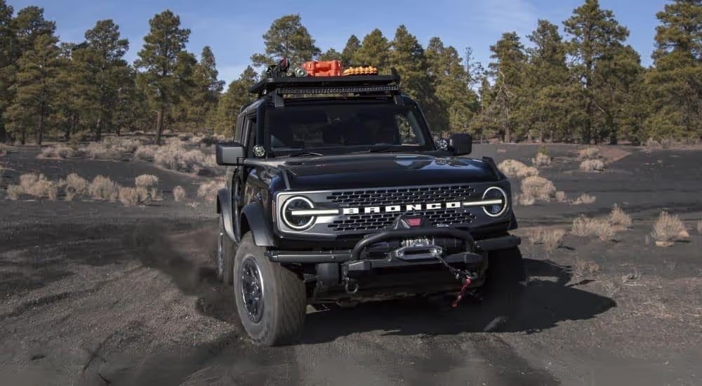 A black 2024 Ford Bronco is shown driving off-road.