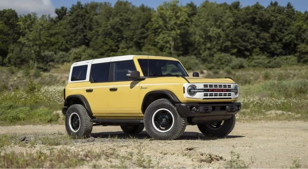 A yellow 2024 Ford Bronco Heritage Edition is shown parked off-road. 